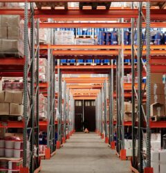 Interior de almacén de fulfillment FBA con estanterías de inventario y cajas de pedidos apiladas en pasillos