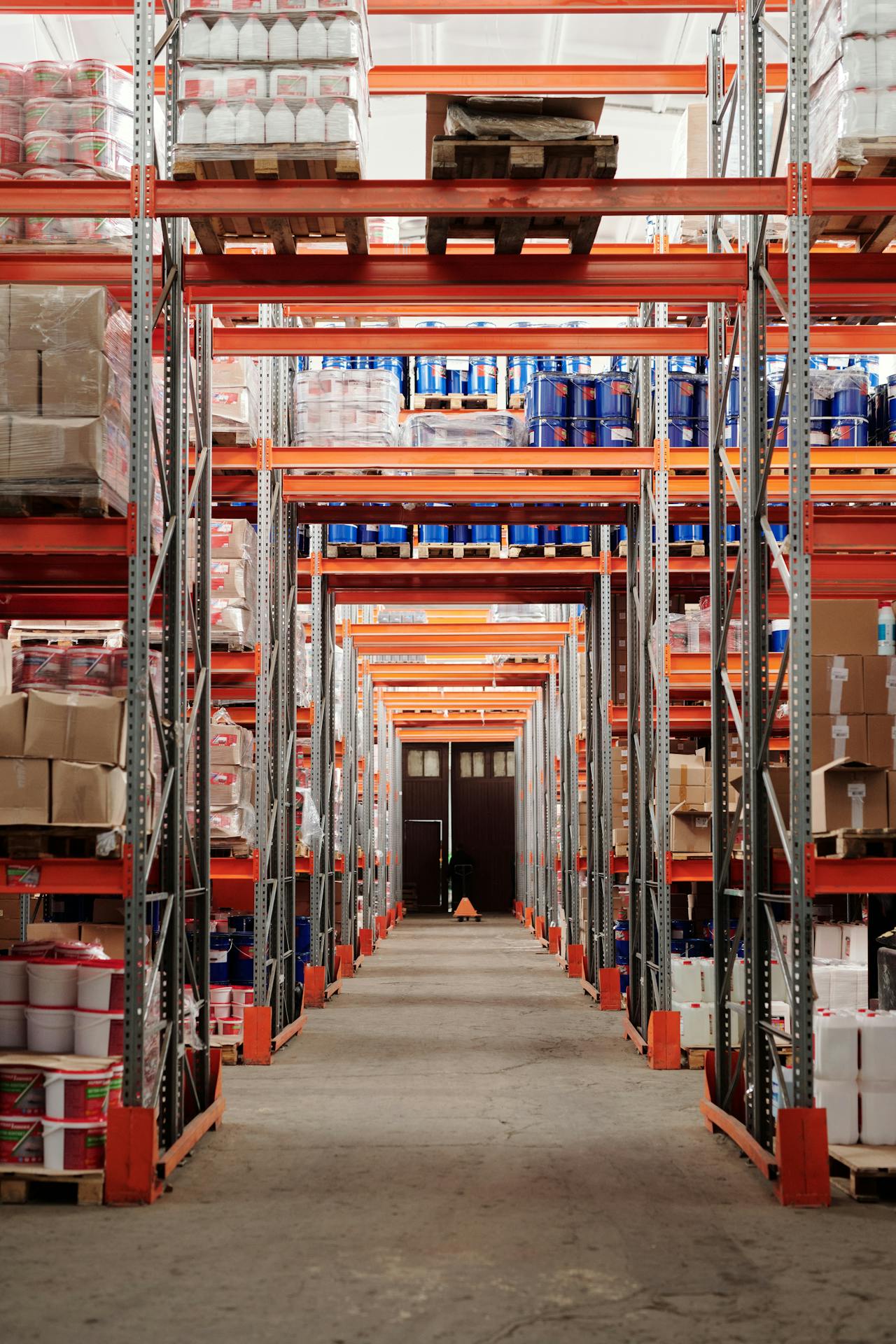 Interior de almacén de fulfillment FBA con estanterías de inventario y cajas de pedidos apiladas en pasillos