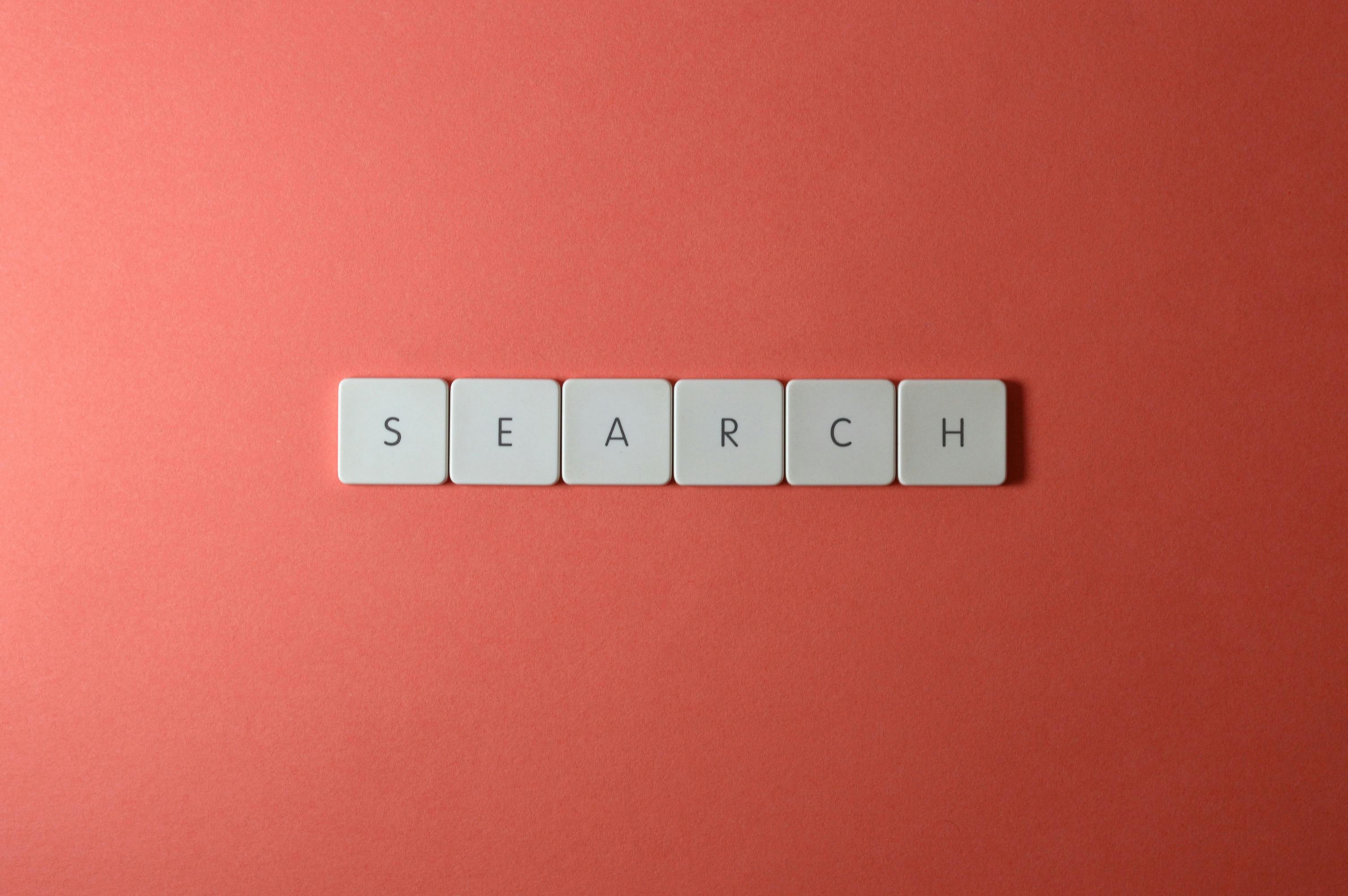 Teclado blanco con teclas que forman la palabra search sobre fondo rojo ilustrando la nueva guía oficial de Google AI Overviews